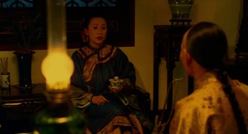 Movie still from “Flowers of Shanghai” (1998), directed by Hsiao-Hsien Hou – A woman in traditional chinese clothing sitting in a chair; Medium shot, Over the shoulder angle