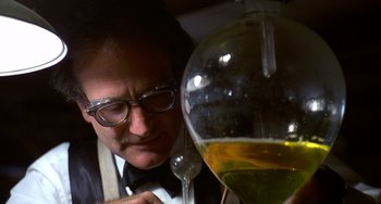 Movie still from “Flubber” (1997), directed by Les Mayfield – A man looking at an olive oil in a glass container; Close Up shot, Low angle