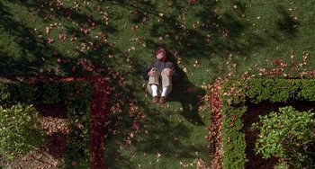 Movie still from “Flubber” (1997), directed by Les Mayfield – A man laying on the grass with a monkey head; Extreme Wide shot, Overhead angle