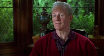Movie still from “Flubber” (1997), directed by Les Mayfield – An older man sitting in a chair wearing a red sweater; Close Up shot, Low angle