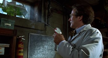 Movie still from “Flubber” (1997), directed by Les Mayfield – A man in a white lab coat holding an object in front of a blackboard; Close Up shot, Low angle