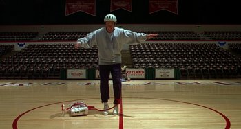 Movie still from “Flubber” (1997), directed by Les Mayfield – An older man is standing on a basketball court; Wide shot, Low angle