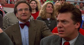 Movie still from “Flubber” (1997), directed by Les Mayfield – Two men and a woman are sitting in a crowd; Close Up shot, Over the shoulder angle