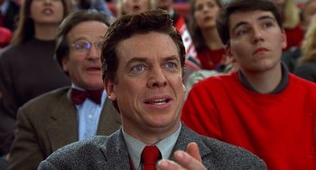 Movie still from “Flubber” (1997), directed by Les Mayfield – A man in a crowd of people wearing a suit and red neck tie; Close Up shot, Low angle