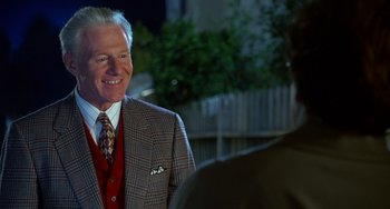 Movie still from “Flubber” (1997), directed by Les Mayfield – A man in a suit and a tie smiling; Medium shot, Over the shoulder angle
