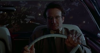 Movie still from “Flubber” (1997), directed by Les Mayfield – A man in a suit and bow tie holding a steering wheel; Close Up shot, Low angle