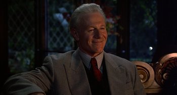 Movie still from “Flubber” (1997), directed by Les Mayfield – An older man in a gray suit and red neck tie; Close Up shot, Low angle