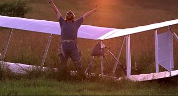 Movie still from “Fly Away Home” (1996), directed by Carroll Ballard – A man standing next to an airplane in a field; Wide shot, Low angle