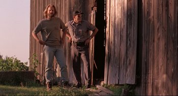 Movie still from “Fly Away Home” (1996), directed by Carroll Ballard – Two men standing next to each other in front of an old barn; Medium shot, Low angle