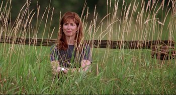 Movie still from “Fly Away Home” (1996), directed by Carroll Ballard – A woman standing in tall grass near a wooden fence; Medium shot, Low angle