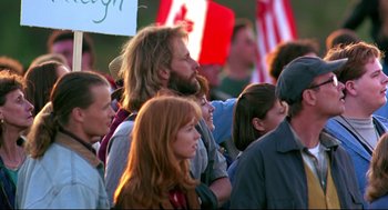 Movie still from “Fly Away Home” (1996), directed by Carroll Ballard – A group of people standing in a crowd holding signs; Medium shot, Low angle