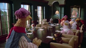Movie still from “Follow That Bird” (1985), directed by Ken Kwapis – A group of people sitting around a table with stuffed animals; Wide shot, High angle