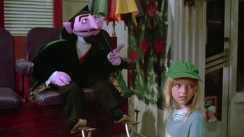 Movie still from “Follow That Bird” (1985), directed by Ken Kwapis – A girl is sitting in front of a puppet; Medium shot, Over the shoulder angle