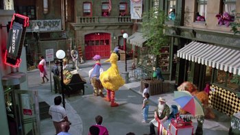 Movie still from “Follow That Bird” (1985), directed by Ken Kwapis – A group of people standing in a street with a big bird costume; Extreme Wide shot, High angle