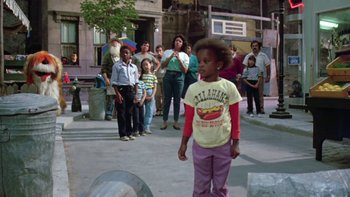 Movie still from “Follow That Bird” (1985), directed by Ken Kwapis – A little girl standing in front of a group of people; Wide shot, Over the shoulder angle