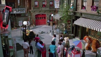 Movie still from “Follow That Bird” (1985), directed by Ken Kwapis – A group of people standing in a courtyard; Extreme Wide shot, High angle