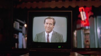 Movie still from “Follow That Bird” (1985), directed by Ken Kwapis – A television screen showing a man in a business suit; Close Up shot, Over the shoulder angle