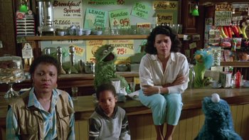 Movie still from “Follow That Bird” (1985), directed by Ken Kwapis – A group of people sitting at a counter; Medium shot, Low angle