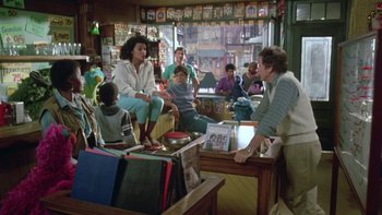 Movie still from “Follow That Bird” (1985), directed by Ken Kwapis – A group of people sitting around a room; Wide shot, Over the shoulder angle