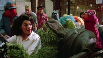 Movie still from “Follow That Bird” (1985), directed by Ken Kwapis – A group of people standing next to each other near a group of stuffed animals; Medium shot, Over the shoulder angle