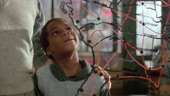 Movie still from “Follow That Bird” (1985), directed by Ken Kwapis – A young boy looking up at a map of a city; Close Up shot, High angle