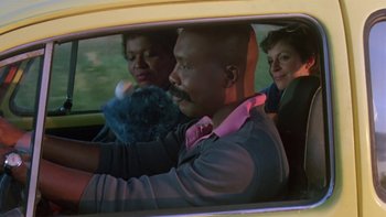 Movie still from “Follow That Bird” (1985), directed by Ken Kwapis – A man and two women in a yellow car; Medium shot, Low angle