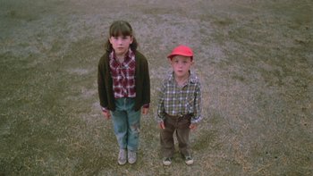 Movie still from “Follow That Bird” (1985), directed by Ken Kwapis – A boy and a girl standing next to each other; Medium shot, High angle