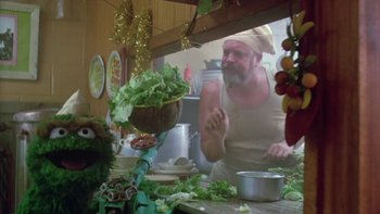Movie still from “Follow That Bird” (1985), directed by Ken Kwapis – A man in a chef's hat is cooking in a kitchen; Medium shot, Low angle