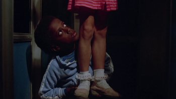 Movie still from “Follow That Bird” (1985), directed by Ken Kwapis – A young boy is holding a little girl's feet; Medium shot, Low angle