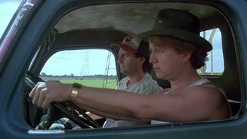 Movie still from “Follow That Bird” (1985), directed by Ken Kwapis – Two men driving a car in a rural area; Medium shot, Low angle