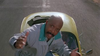 Movie still from “Follow That Bird” (1985), directed by Ken Kwapis – A man in a yellow car on the street; Medium shot, Low angle