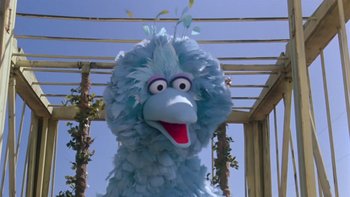 Movie still from “Follow That Bird” (1985), directed by Ken Kwapis – A big blue stuffed bird is standing under a pergola; Close Up shot, Low angle
