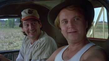 Movie still from “Follow That Bird” (1985), directed by Ken Kwapis – Two men are posing for a picture while wearing baseball uniforms; Close Up shot, Low angle
