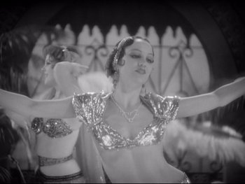 Movie still from “Footlight Parade” (1933), directed by Lloyd Bacon – A woman in an oriental dance outfit with her arms outstreched; Medium shot, High angle