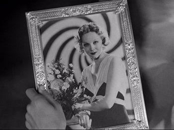 Movie still from “Footlight Parade” (1933), directed by Lloyd Bacon – An old photo of a woman holding a vase of flowers; Close Up shot, Overhead angle
