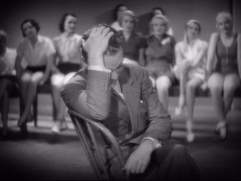 Movie still from “Footlight Parade” (1933), directed by Lloyd Bacon – A man sitting in a chair with his head in his hand; Medium shot, High angle