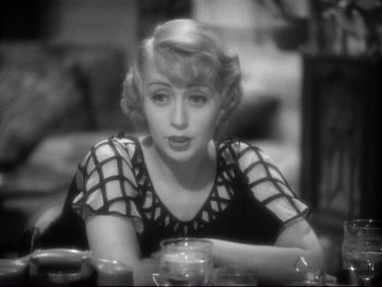 Movie still from “Footlight Parade” (1933), directed by Lloyd Bacon – A black and white photo of a woman sitting at a table; Close Up shot, High angle