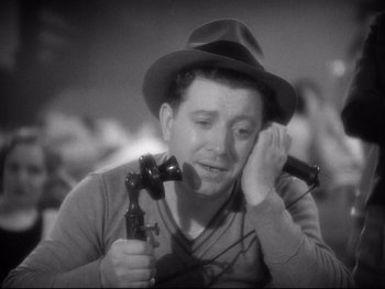 Movie still from “Footlight Parade” (1933), directed by Lloyd Bacon – A black and white photo of a man holding a phone; Close Up shot, High angle