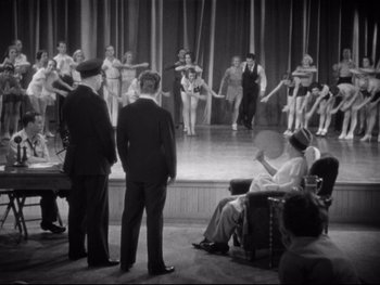 Movie still from “Footlight Parade” (1933), directed by Lloyd Bacon – A group of men standing on a stage with women; Wide shot, High angle
