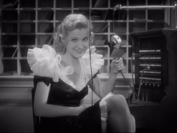 Movie still from “Footlight Parade” (1933), directed by Lloyd Bacon – A black and white photo of a woman holding a microphone; Medium shot, Low angle