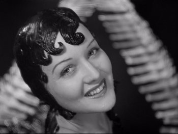 Movie still from “Footlight Parade” (1933), directed by Lloyd Bacon – A black and white photo of a woman smiling for the camera; Close Up shot, High angle