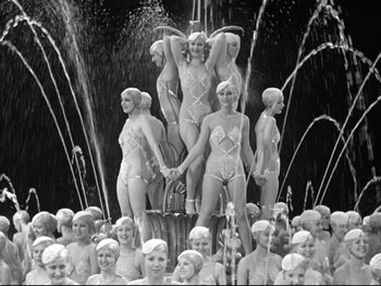 Movie still from “Footlight Parade” (1933), directed by Lloyd Bacon – A group of women in bathing suits standing in front of a fountain; Wide shot, High angle