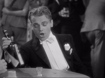 Movie still from “Footlight Parade” (1933), directed by Lloyd Bacon – A man in a tuxedo sitting at a table with a glass; Medium shot, High angle