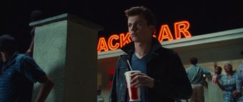 Movie still from “Footloose” (2011), directed by Craig Brewer – A young man holding a drink in his hand; Medium shot, Over the shoulder angle