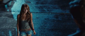 Movie still from “Footloose” (2011), directed by Craig Brewer – A woman in a gray tank top is standing on the street; Medium shot, Over the shoulder angle