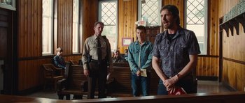 Movie still from “Footloose” (2011), directed by Craig Brewer – A group of men standing in front of a courtroom; Medium shot, Over the shoulder angle