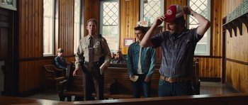 Movie still from “Footloose” (2011), directed by Craig Brewer – Three men stand in a court room , one of whom is holding an object in his hand; Medium shot, Over the shoulder angle