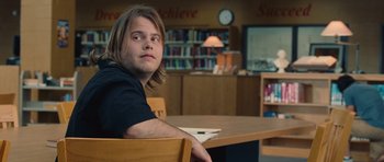 Movie still from “Footloose” (2011), directed by Craig Brewer – A man sitting at a table in front of books; Close Up shot, Over the shoulder angle