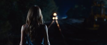Movie still from “Footloose” (2011), directed by Craig Brewer – A woman standing in front of a train at night; Medium shot, Over the shoulder angle