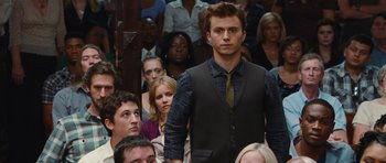 Movie still from “Footloose” (2011), directed by Craig Brewer – A crowd of people sitting in a room with a man in a vest; Medium shot, Over the shoulder angle